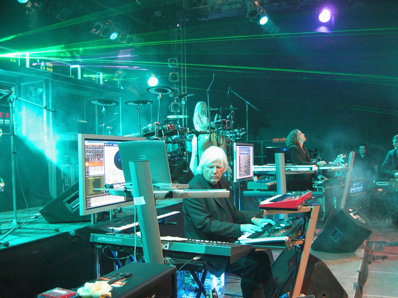 Tangerine Dream auf einer Bühne, durchzogen von grünen Laserstrahlen, Edgar Froese an den Keyboards in der Mitte